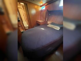 Cozy interior view of a boat cabin featuring a double bed and adjoining bathroom, perfect for comfortable overnight stays on the water.