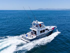 A sleek speedboat named 'Catch Me!' navigates through clear blue waters, showcasing its impressive design and performance on the open sea.
