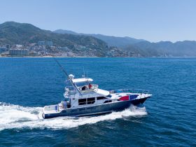 A stunning aerial view of a yacht cruising through clear blue waters, showcasing the beautiful coastline in the background — perfect for luxury charters and scenic tours.