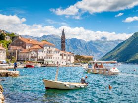 A picturesque harbor scene featuring charming boats and stunning mountain backdrops, perfect for capturing the essence of coastal adventures.