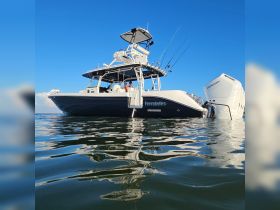 A sleek fishing boat named 'Everglades' is anchored on calm waters, with two people visible enjoying the day — perfect for fishing adventures and outdoor excursions.