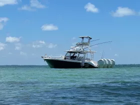A sleek speedboat anchored in clear turquoise waters, showcasing its modern design and fishing equipment — perfect for adventurous outings on the water.