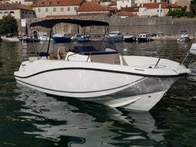 A sleek speedboat docked in calm waters, showcasing its modern design and inviting seating — perfect for a day on the water.