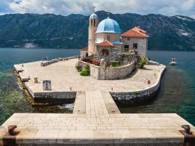 A picturesque view of a charming island landmark surrounded by clear waters and mountains, perfect for exploring the stunning coastline.