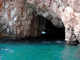 A stunning view of a natural cave along the coastline, with crystal-clear turquoise waters inviting exploration — perfect for eco tours and scenic boat trips.