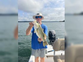 A proud angler displays a large bass caught while fishing on a boat, showcasing the thrill of a successful day on the water.