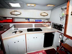 Interior view of a boat's cabin showcasing the helm area, complete with a sink, storage, and essential equipment — perfect for comfortable cruising.