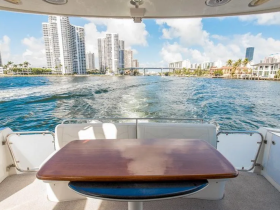 A cozy interior view of a boat's seating area, showcasing a polished table and a scenic backdrop of waterfront buildings, perfect for relaxing while cruising.