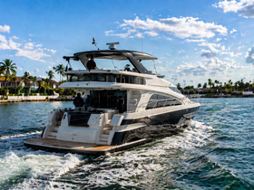 A stunning yacht glides through the water, showcasing its sleek design and elegance against a backdrop of palm trees and blue skies.
