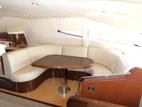 A cozy interior lounge area of a yacht featuring comfortable seating and a polished table, perfect for relaxing during a day on the water.