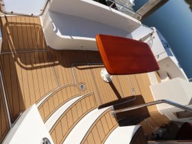 A detailed view of the interior deck of a boat, showcasing the elegant wooden table and well-maintained flooring, perfect for relaxing or entertaining guests.