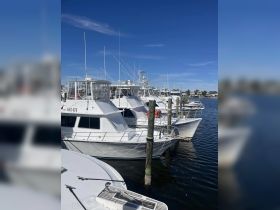 A collection of boats docked at a marina under a clear blue sky, showcasing various vessel designs and structures.