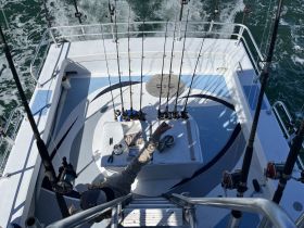 A well-equipped fishing boat deck featuring multiple rod holders and gear, perfect for a day of deep-sea fishing adventures.