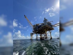 An industrial structure rises above the water, captured from a boat, showcasing the unique offshore scenery.