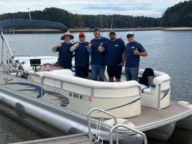 A group of friends poses on a pontoon boat, showcasing their excitement for a day of fishing and fun on the water.