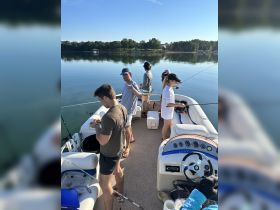 A group of friends enjoys a fishing trip on a boat, showcasing camaraderie and the thrill of the catch on a serene lake.