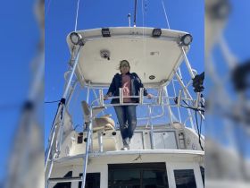 A woman stands at the helm of a boat, showcasing the interior design and control area, perfect for navigating the open waters.