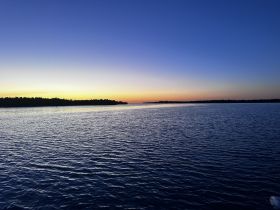 A stunning sunset over calm waters, showcasing the serene beauty of the coastline — perfect for peaceful evening cruises.