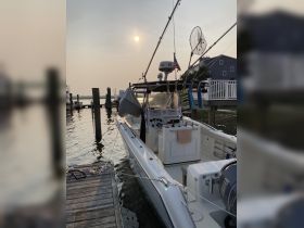 A sleek speedboat docked at sunset, showcasing its streamlined hull and fishing gear, perfect for a day on the water.