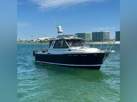 A sleek yacht cruising through clear waters, showcasing its elegant design against a backdrop of coastal buildings.