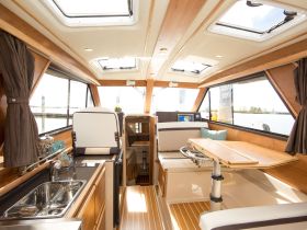 A beautifully designed interior of a boat featuring a helm, seating area, and modern amenities, perfect for comfortable cruising and relaxation on the water.