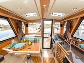 A beautifully designed interior of a boat featuring a dining area with elegant table settings, perfect for enjoying meals while cruising.