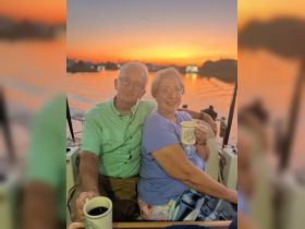 A couple enjoys a cozy moment with drinks while watching the sunset from their boat, capturing the essence of romantic evenings on the water.