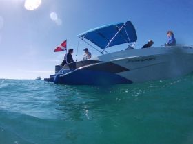 Two individuals engage on a Starcraft boat, with a diving flag visible, showcasing a perfect day on the water for diving or exploration.