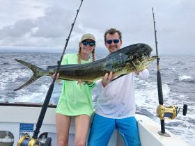 A couple proudly displays their impressive catch while fishing on the open ocean, showcasing the thrill of deep-sea fishing adventures.