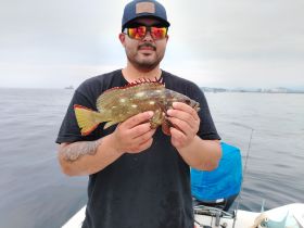 A man proudly displays his catch while fishing on the open ocean, showcasing the thrill of a successful fishing trip.