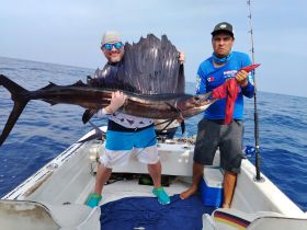 Two anglers proudly display their impressive marlin catch aboard a fishing boat, showcasing the thrill of deep-sea fishing adventures.