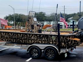 A striking side view of a camouflaged boat on a trailer, showcasing its unique design and features, perfect for fishing enthusiasts.