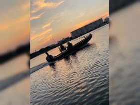 A fishing boat navigates through calm waters at sunset, creating a picturesque scene perfect for evening excursions.