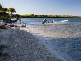 A serene beach scene featuring a small boat near the shore, perfect for a relaxing fishing day surrounded by nature.
