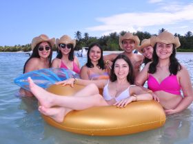 A lively group of friends enjoys a fun day at the beach, relaxing in the water and soaking up the sun — perfect for summer celebrations and beach outings.