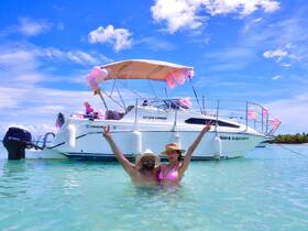 A joyful couple celebrates in the clear waters beside their decorated boat, creating a perfect backdrop for memorable moments and fun on the water.