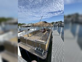A well-equipped tiki boat featuring a shaded bar area with seating, perfect for relaxing on the water. Ideal for entertaining guests during sunny outings.