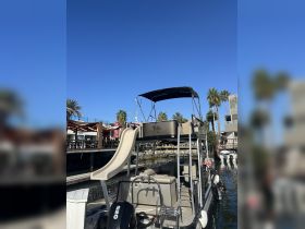 A sleek pontoon boat featuring a water slide, docked and ready for fun on the water. Perfect for family outings and summer adventures.