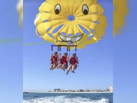 A group of friends enjoys an exhilarating parasailing adventure over the ocean, capturing the thrill of summer fun and adventure in the sun.