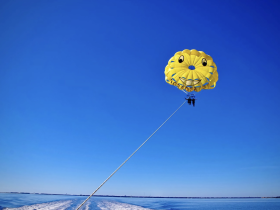 A thrilling parasailing adventure over sparkling waters, showcasing the excitement of on-water activities against a clear blue sky.