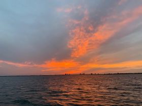 A stunning sunset paints the sky in vibrant hues over the water, creating a picturesque backdrop for evening boat trips and coastal adventures.