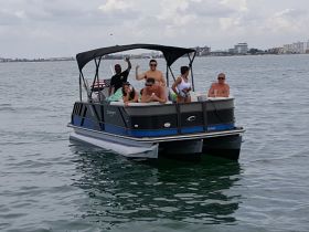 A lively group enjoys a day out on a pontoon boat, celebrating and having fun on the water — perfect for summer outings and gatherings.