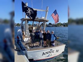 A group of friends poses on the deck of the 'Annie M' fishing boat, celebrating their day on the water in Gloucester, MA. Perfect for fishing trips and group outings.