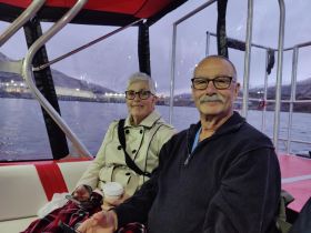 A cozy interior shot of a couple enjoying their time aboard a boat, showcasing the comfortable seating and scenic views through the windows.