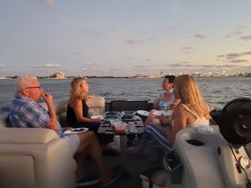 A group of friends enjoys a sunset dinner on a pontoon boat, creating memorable moments on the water with great food and company.