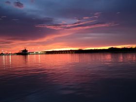 A stunning sunset over the harbor, reflecting vibrant colors on the water's surface — a picturesque moment perfect for evening boat cruises.