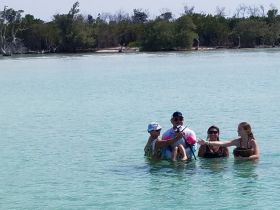 A lively group enjoys a fun day in the shallow waters, showcasing a memorable beach experience filled with laughter and camaraderie.