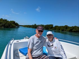 A cheerful couple enjoys a scenic boat ride through lush mangroves, capturing the essence of adventure on the water.