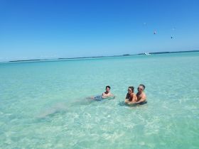 A group of friends enjoys a refreshing swim in the crystal-clear waters, capturing the essence of a perfect beach day.