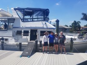A cheerful group poses in front of their boat, ready for a day of fun on the water. Perfect for family outings or group adventures.